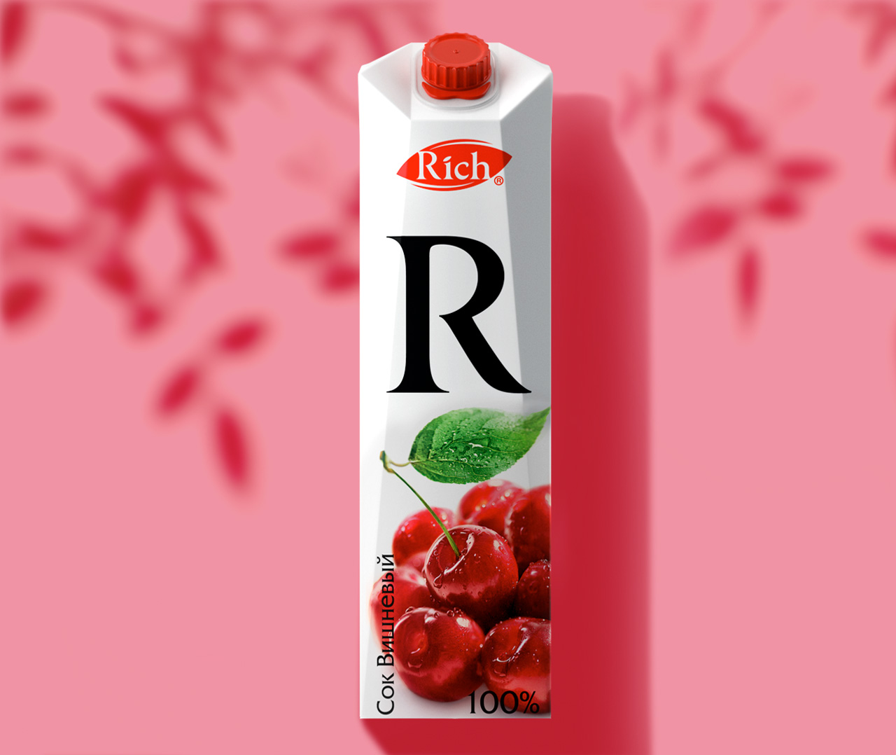 Картонная упаковка вишневого сока Rich с большой буквой R, зеленым листом и вишнями на лицевой стороне, а также фирменным знаком Soldis на розовом фоне с красными тенями от листьев.