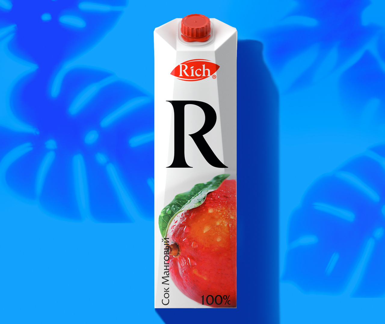 Прямоугольная картонная упаковка мангового сока Rich с красной крышкой, на которой изображены большая буква R, изображение спелого манго, кириллический текст и логотип Soldis на синем фоне с тенями тропических листьев.
