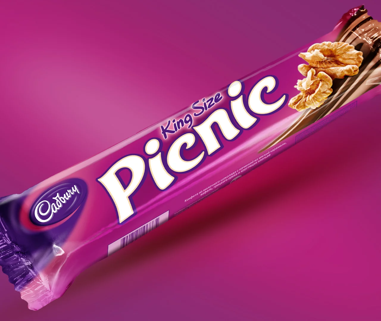 Шоколадный батончик Cadbury King Size Picnic в фиолетовой обертке представлен на соответствующем фиолетовом фоне с названием батончика и изображениями орехов и карамели на упаковке. Брендинг Soldis добавляет уникальный штрих презентации.