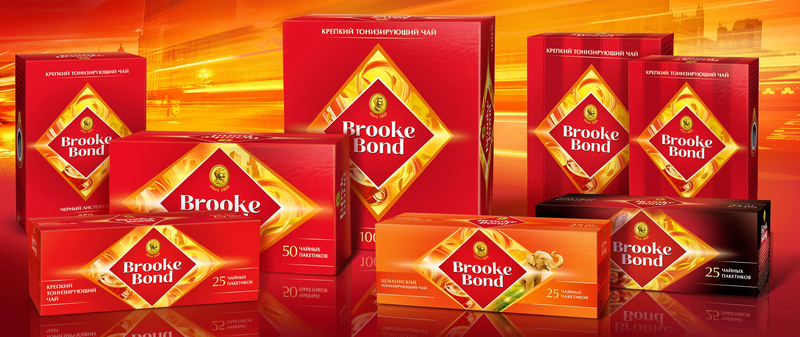 Несколько красных и оранжевых коробок чая Brooke Bond выставлены на ярком оранжевом фоне. На коробках, на которых изображен ромбовидный золотой и белый логотип Soldis, указано название бренда на русском и английском языках.