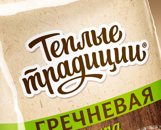 Крупный план упаковки «Сольдис» с русским текстом «Тёплые традиции», написанным коричневым шрифтом, и словом «ГРЕЧНЕВАЯ», написанным жирными зелеными буквами ниже на светло-бежевом фоне.