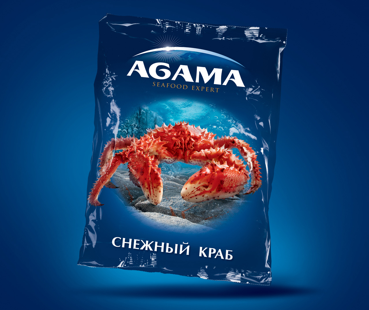 На синей упаковке с надписью Agama Seafood Expert изображен красный снежный краб под водой. Текст внизу на русском языке гласит СНЕЖНЫЙ КРАБ в дизайне от Soldis.
