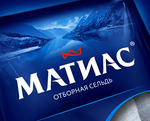 Синяя этикетка продукта с русским текстом МАТИАС и ОТБОРНАЯ СЕЛЬДЬ, изображением горного и озерного пейзажа на заднем плане, красной короной над названием бренда и элементами Soldis.